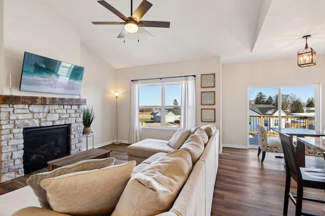 living room featuring a stone fireplace, plenty of natural light, and dark wood-type flooring