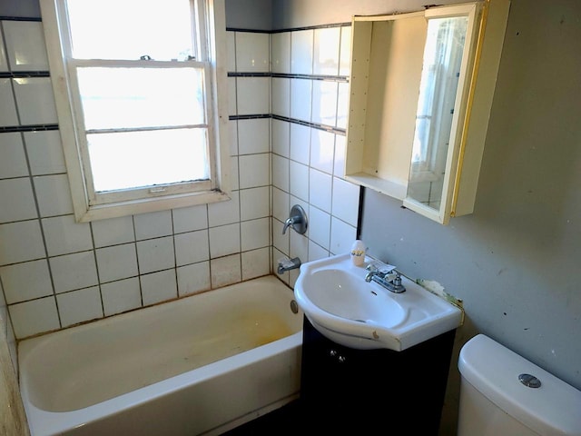 full bathroom featuring tiled shower / bath, vanity, and toilet