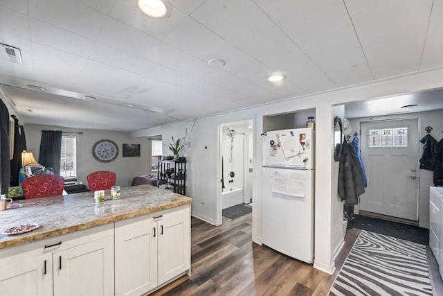 kitchen with white cabinetry, light stone counters, dark hardwood / wood-style flooring, white fridge, and a healthy amount of sunlight