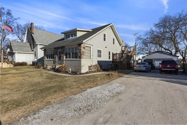 view of property exterior with an outbuilding, a garage, a lawn, and a sunroom