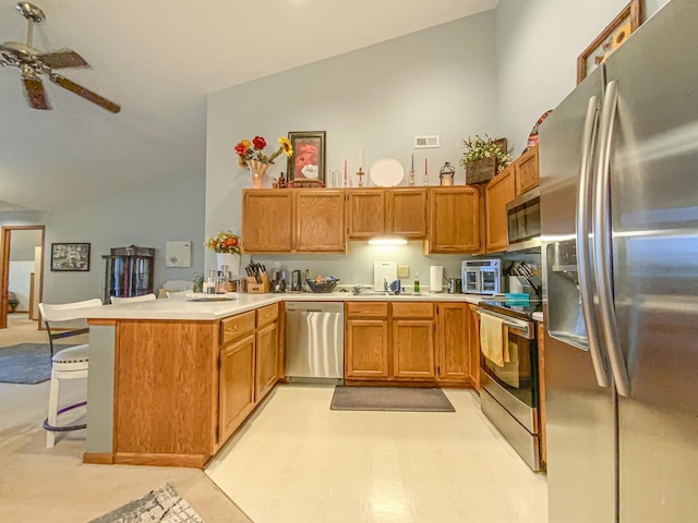 kitchen with ceiling fan, appliances with stainless steel finishes, high vaulted ceiling, a kitchen breakfast bar, and kitchen peninsula