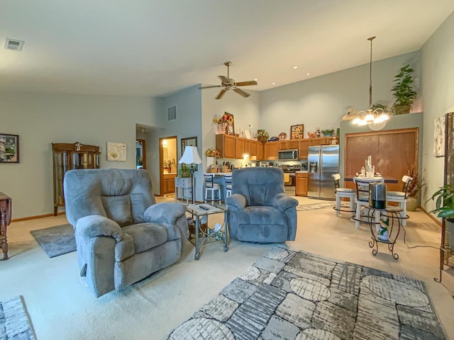 carpeted living room with ceiling fan with notable chandelier and high vaulted ceiling