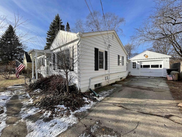 snow covered property featuring a garage and an outdoor structure