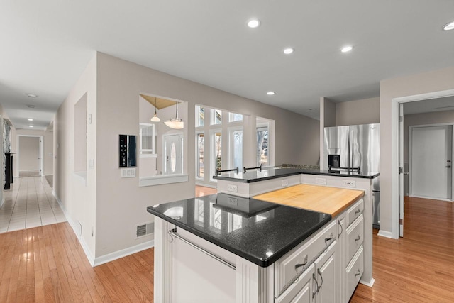 kitchen featuring stainless steel fridge, a kitchen island, white cabinets, and light hardwood / wood-style flooring