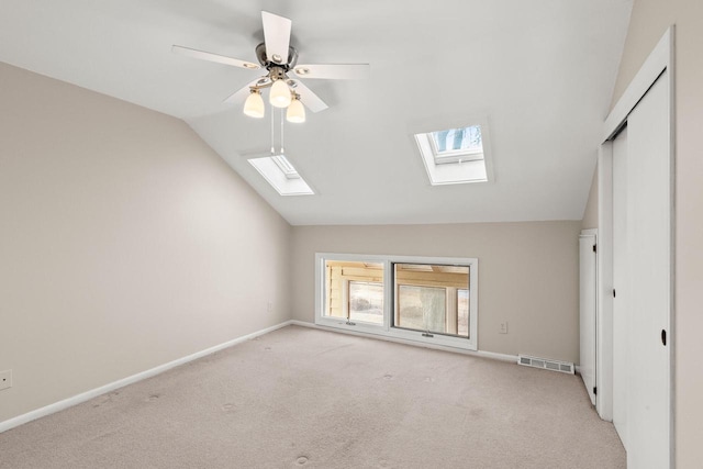 unfurnished bedroom with lofted ceiling with skylight, light colored carpet, ceiling fan, and a closet