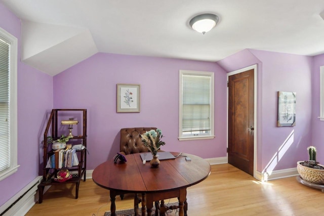 dining room featuring baseboards, baseboard heating, light wood-style flooring, and vaulted ceiling