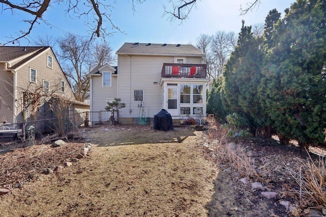 rear view of house with a balcony and fence