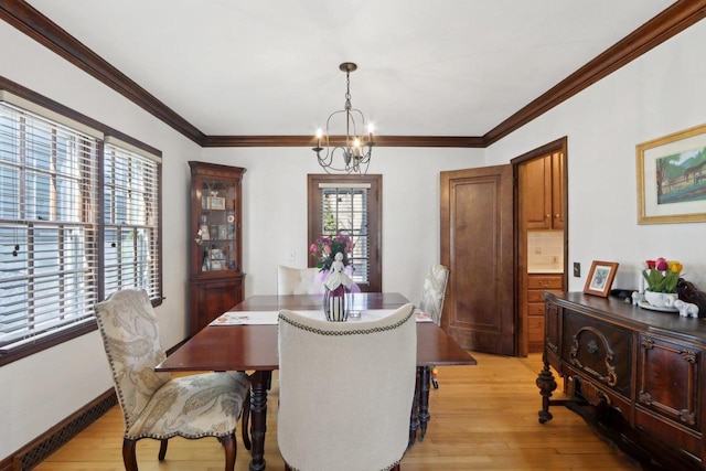 dining area with baseboards, an inviting chandelier, crown molding, and light wood finished floors