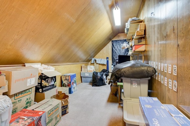 interior space featuring carpet flooring, wooden walls, and vaulted ceiling