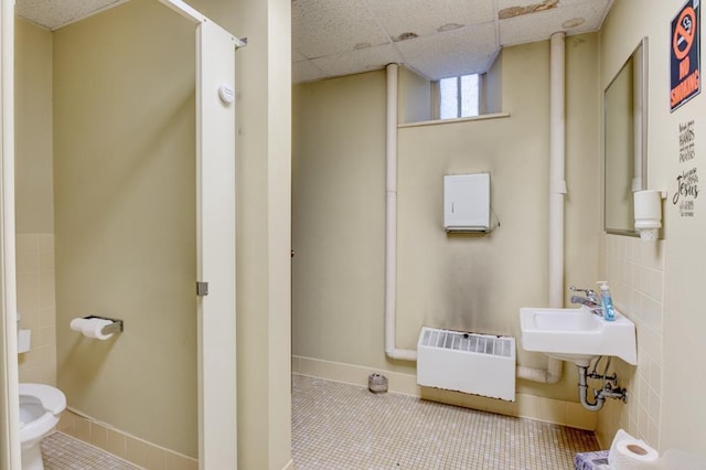 bathroom with radiator heating unit, tile patterned flooring, sink, and a drop ceiling