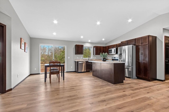 kitchen with a kitchen island, appliances with stainless steel finishes, lofted ceiling, and light hardwood / wood-style flooring