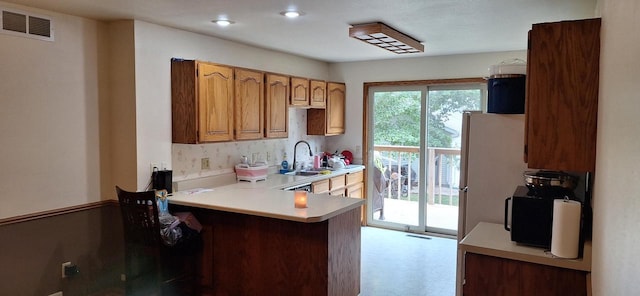 kitchen with sink, kitchen peninsula, and white fridge