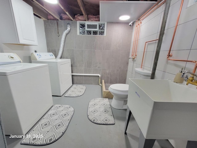 laundry room featuring sink, tile walls, and washing machine and clothes dryer