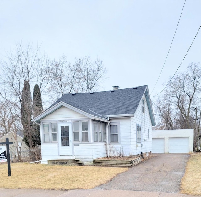 bungalow featuring a garage, an outdoor structure, and a front lawn