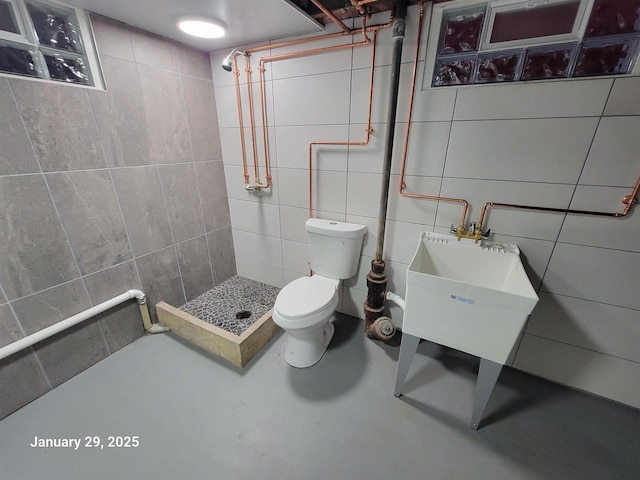 bathroom with tile walls, sink, concrete floors, and toilet