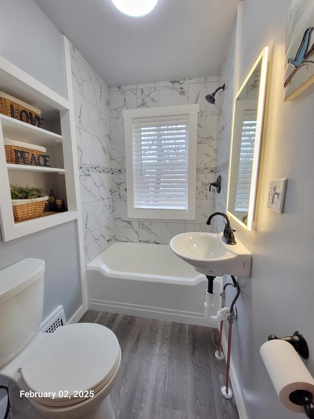 full bathroom featuring tiled shower / bath combo, wood-type flooring, sink, and toilet