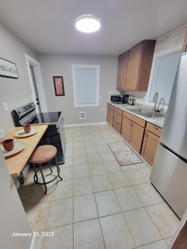 kitchen featuring stainless steel appliances, sink, and light tile patterned floors