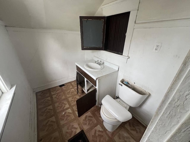 bathroom featuring vanity, parquet flooring, and toilet