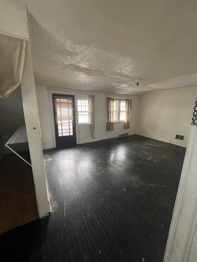 unfurnished room with hardwood / wood-style flooring and a textured ceiling