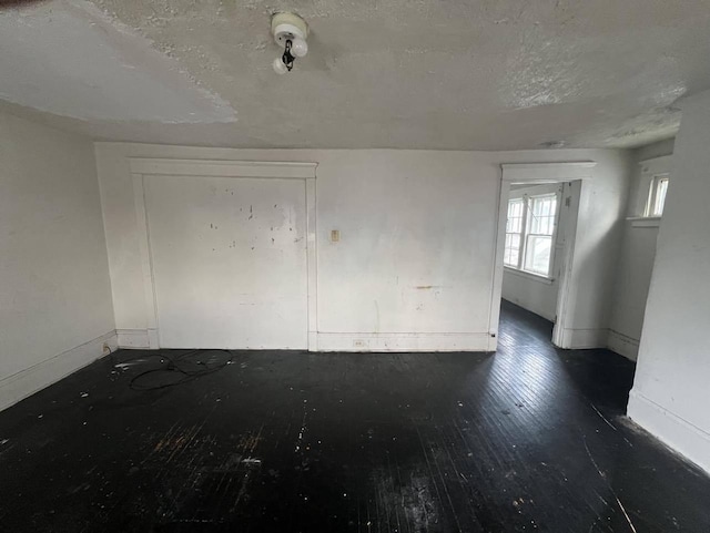 unfurnished room featuring dark wood-type flooring and a textured ceiling