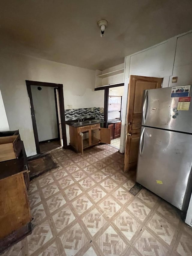 kitchen featuring light parquet flooring, sink, stainless steel fridge, and decorative backsplash