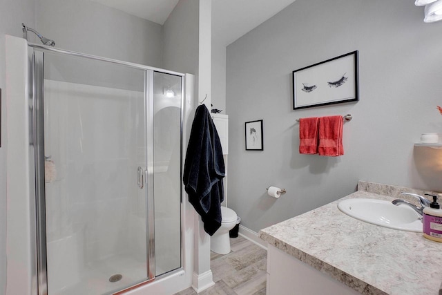 bathroom featuring hardwood / wood-style flooring, vanity, toilet, and a shower with shower door