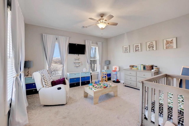 carpeted bedroom with a nursery area and ceiling fan