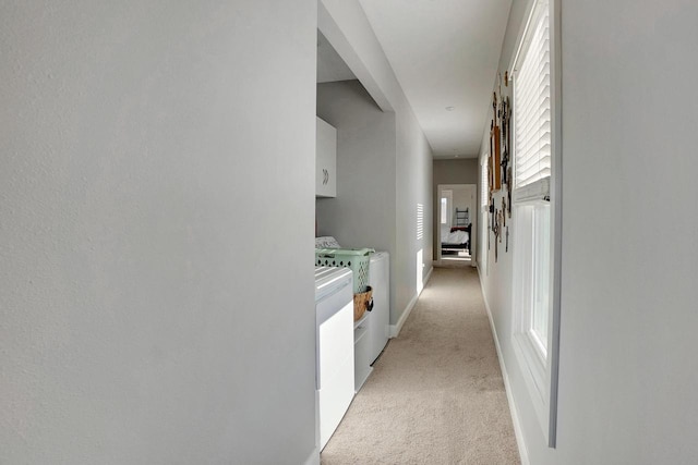 corridor featuring light carpet and washer and dryer