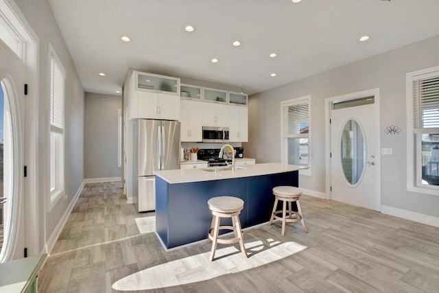 kitchen with sink, a breakfast bar, appliances with stainless steel finishes, an island with sink, and white cabinets