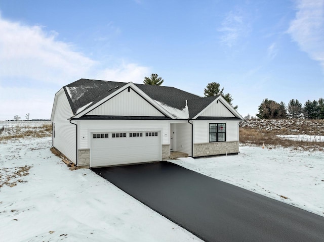 view of front of house featuring a garage, stone siding, driveway, and a shingled roof