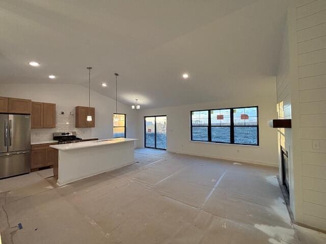 kitchen with open floor plan, light countertops, appliances with stainless steel finishes, brown cabinets, and a glass covered fireplace