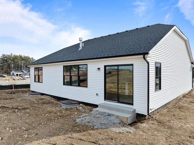 back of property with entry steps and roof with shingles