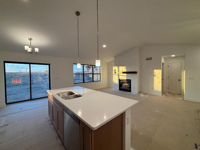 kitchen featuring vaulted ceiling, decorative light fixtures, dishwasher, a large fireplace, and a kitchen island with sink