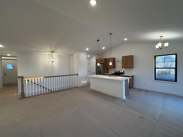 kitchen featuring pendant lighting, stainless steel appliances, a notable chandelier, a kitchen island, and vaulted ceiling