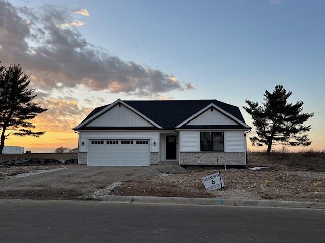 view of front of property with a garage, stone siding, and driveway