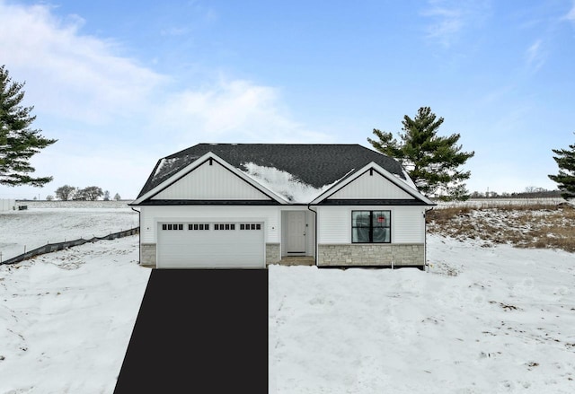 modern farmhouse featuring a garage, stone siding, and driveway