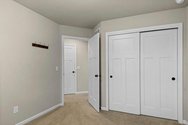 unfurnished bedroom featuring light carpet and a closet