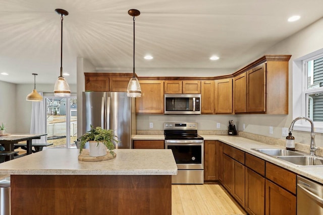 kitchen featuring sink, decorative light fixtures, a center island, light hardwood / wood-style flooring, and stainless steel appliances