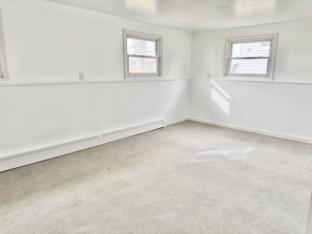 empty room featuring baseboard heating, a healthy amount of sunlight, and carpet flooring