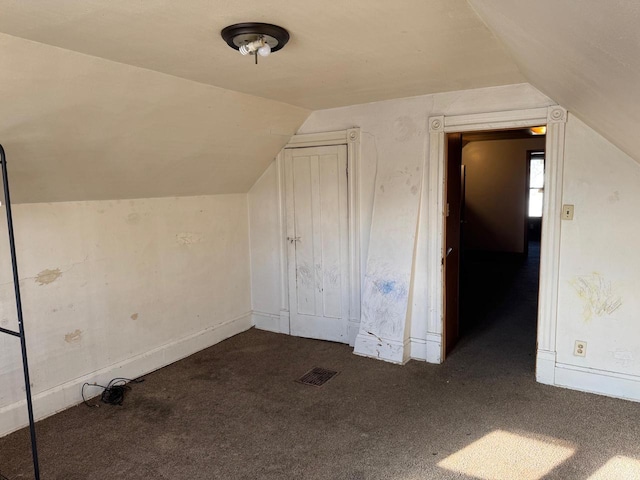 additional living space with dark carpet and vaulted ceiling