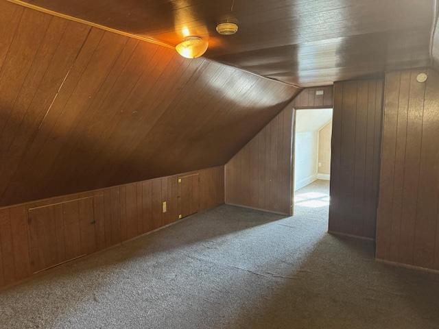 additional living space with wooden walls, wooden ceiling, vaulted ceiling, and carpet