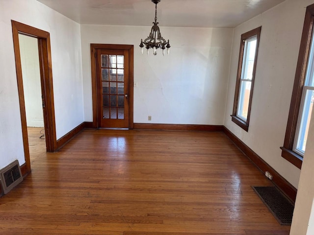 unfurnished dining area featuring dark wood-type flooring and a chandelier