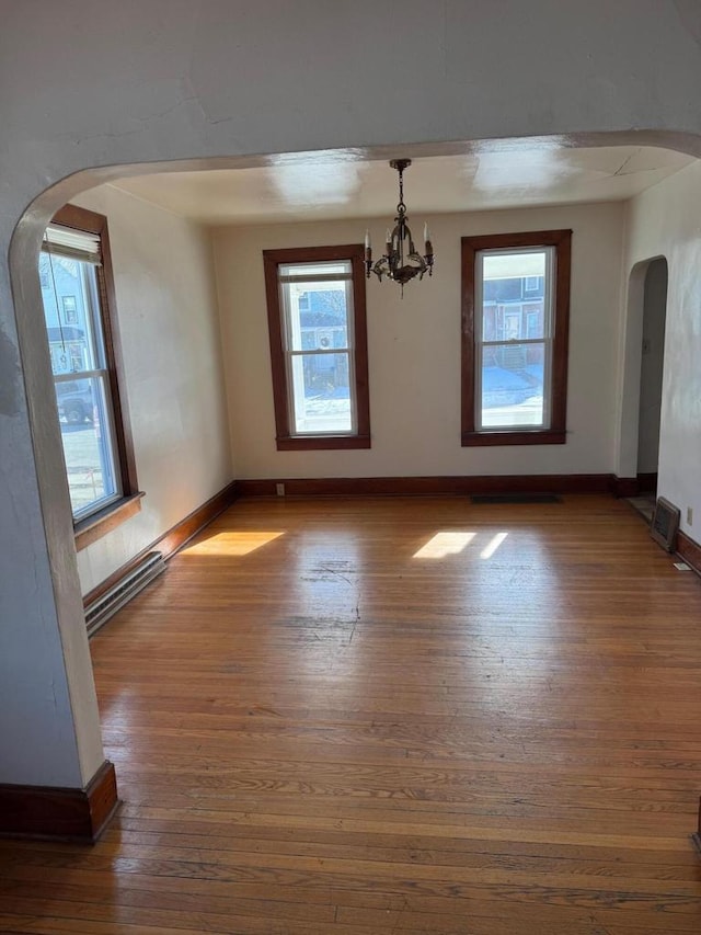 unfurnished dining area featuring baseboard heating, dark hardwood / wood-style flooring, and a notable chandelier