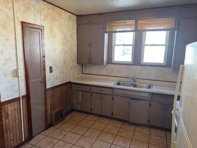 kitchen with white refrigerator, sink, and light tile patterned floors