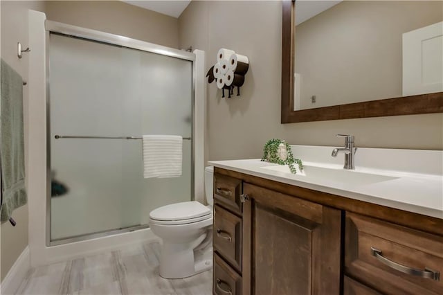 bathroom with vanity, toilet, and a shower with door