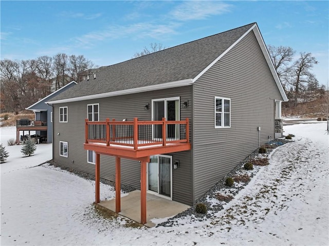 snow covered rear of property with a wooden deck