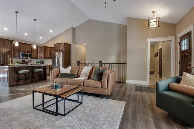 living room with high vaulted ceiling, dark hardwood / wood-style flooring, and sink