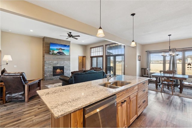 kitchen featuring light stone countertops, a kitchen island with sink, stainless steel dishwasher, and decorative light fixtures