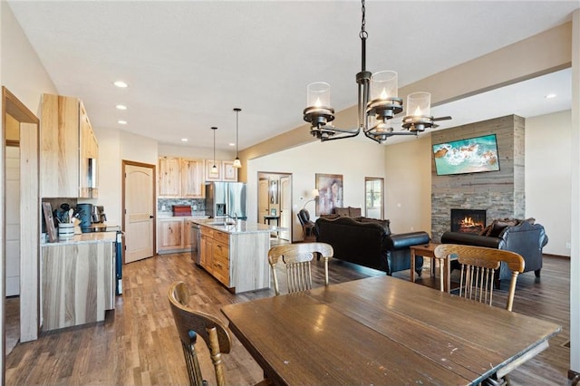 dining room with dark hardwood / wood-style flooring, a chandelier, sink, and a stone fireplace