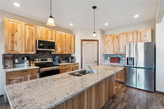 kitchen with light stone counters, sink, decorative light fixtures, and appliances with stainless steel finishes